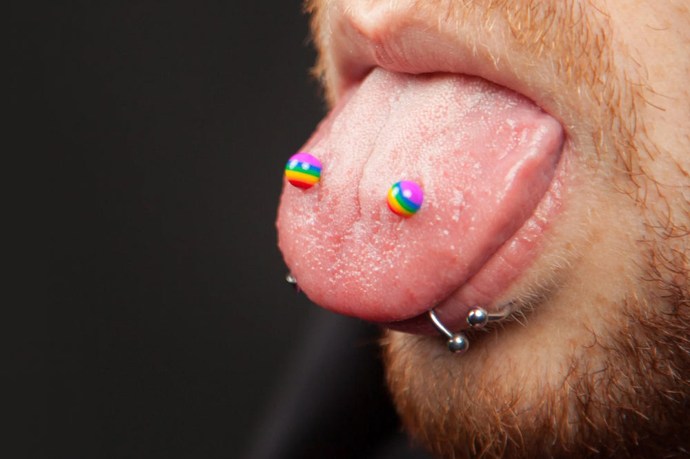 A man sticking his tongue out to show his frogs eyes tongue piercing